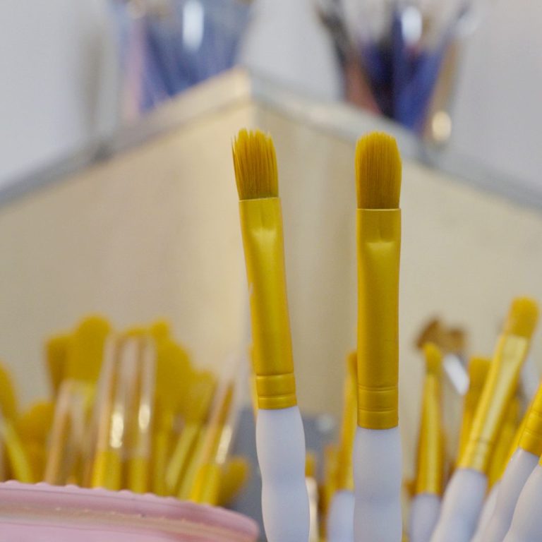 Keramik bemalen Bunte Pinsel mit gelben Griffen stehen in einem Behälter.