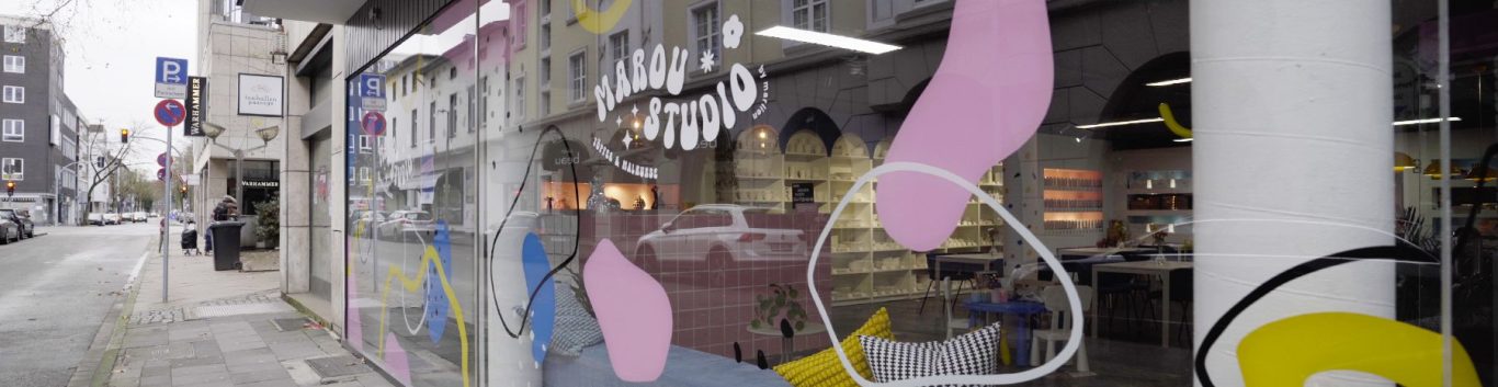 Marou Studio - Außen Schaufenster mit bunten Mustern und einem Blick auf die Straße.